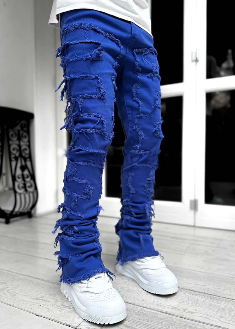 Men's blue stacked jeans with unique patched design and distressed details, stylish long fit trousers.