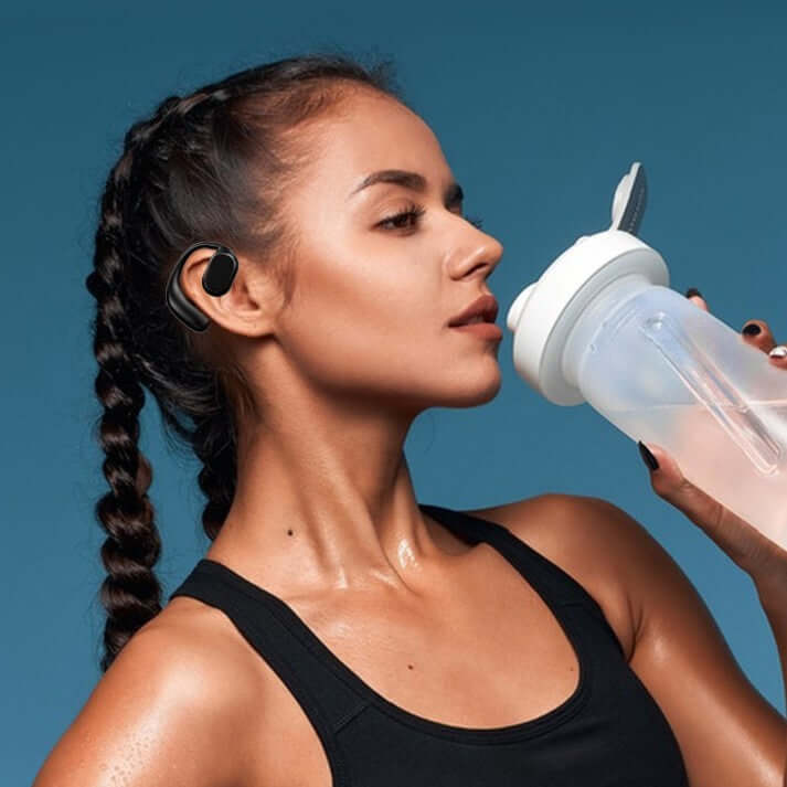 Woman with wireless sports headphones drinking from a shaker bottle, showcasing a fitness lifestyle.