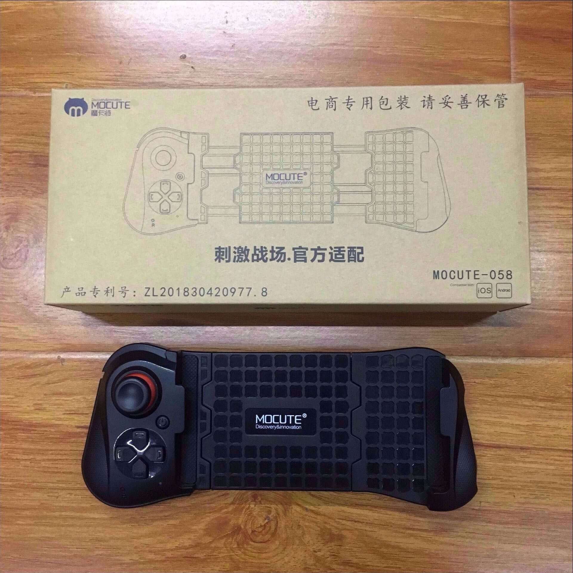 MOCUTE-05B gamepad with ergonomic design and durable materials, packaged in a cardboard box on a wooden surface.