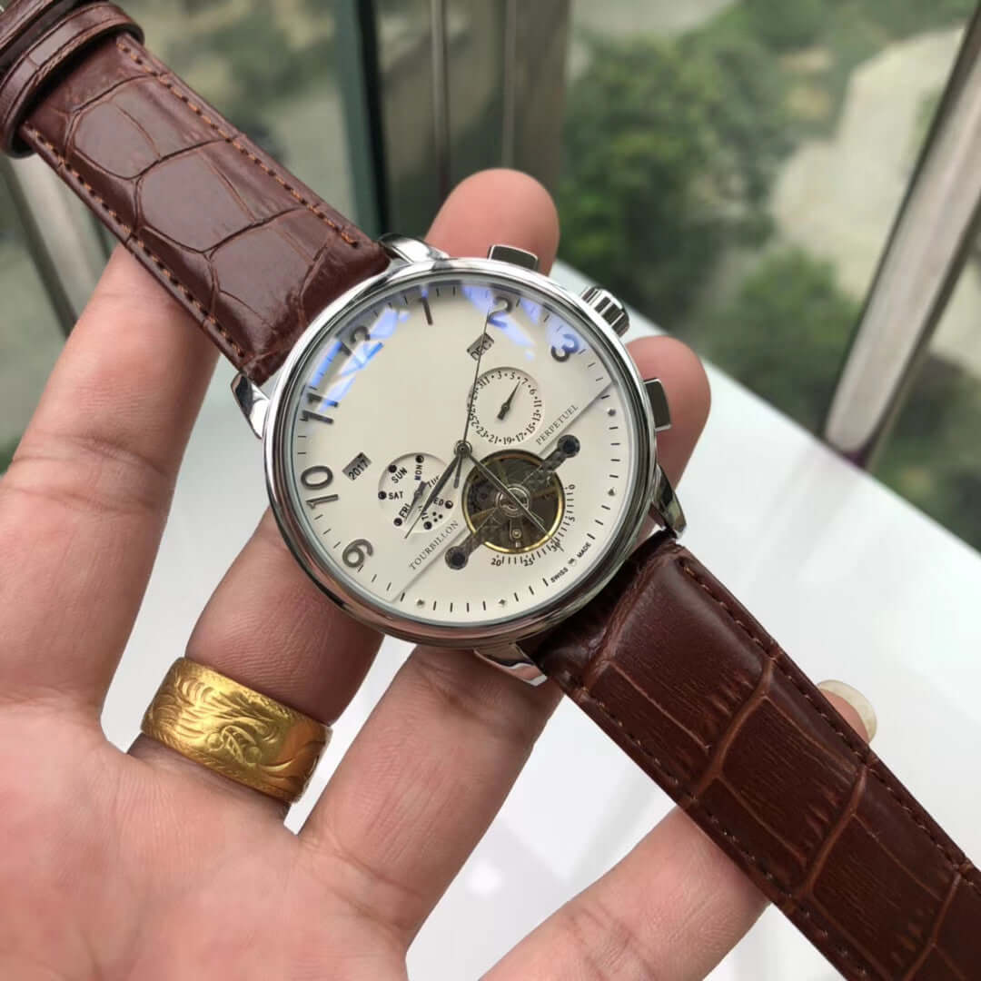 Big flywheel mechanical watch with stainless steel case and brown leather strap, featuring a round dial and calendar display.
