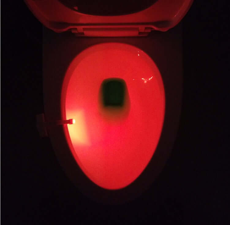 Night view of a toilet with an LED induction night light illuminating it in red.