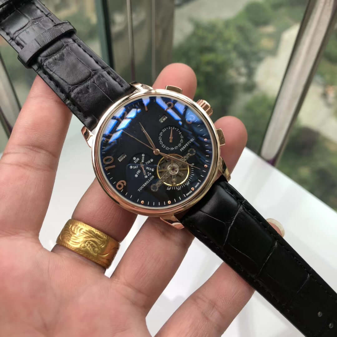 Big flywheel mechanical watch with black leather strap and round dial, featuring calendar display and stainless steel case.