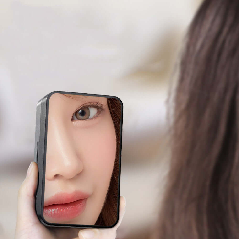 Close-up of a person using a handheld mirror to check their reflection in soft lighting.