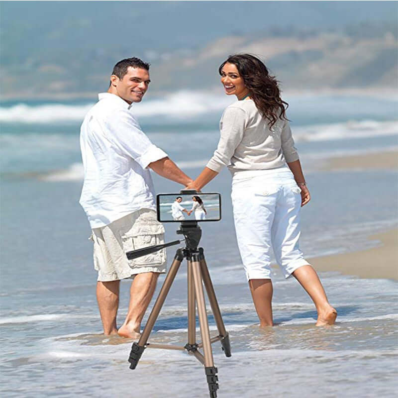 Couple enjoying a beach day with a mobile phone mounted on a tripod for capturing live photos.