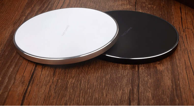 Two wireless fast charge chargers: a white and a black charging pad on a wooden surface.