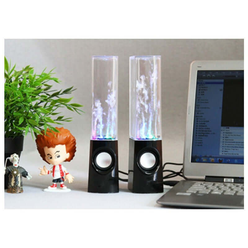 Wireless dancing water speaker with LED lights, compact design, placed beside a plant and figurines on a desk.