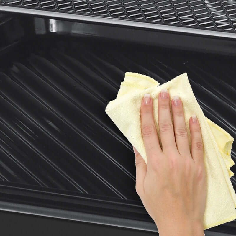 Hand cleaning the interior of a Geek Chef Air Fryer with a yellow cloth to maintain its quality.