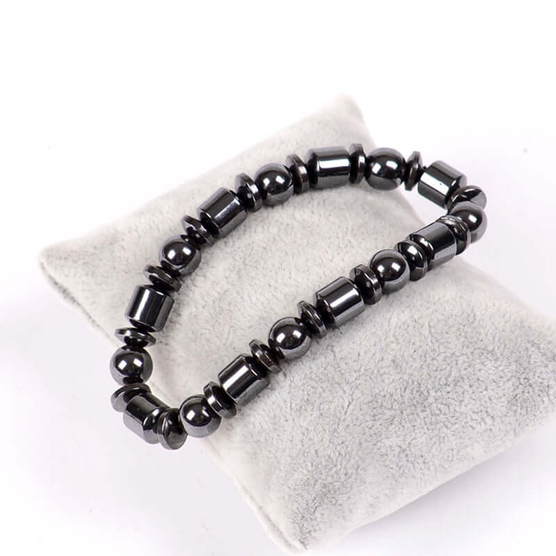 Weight loss black stone magnetic therapy bracelet displayed on a soft gray pad, designed to enhance circulation and metabolism.