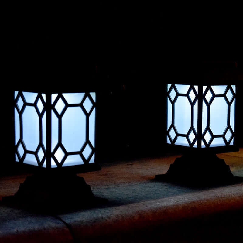 Solar powered courtyard lamps with lattice design, providing warm white light in a garden setting.