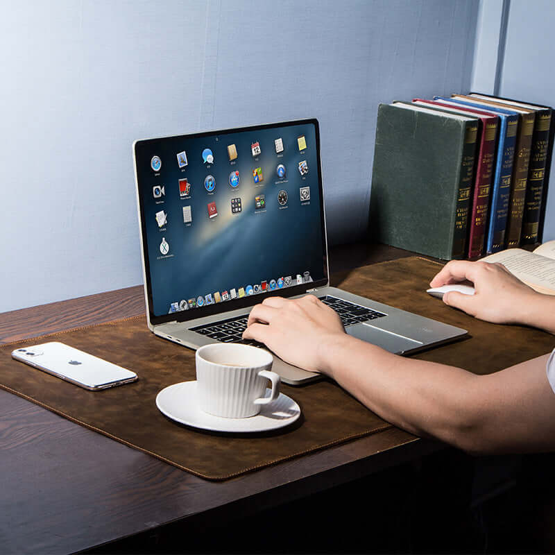 Extra large non-slip desktop leather pad with laptop, coffee cup, and smartphone on a wooden desk.