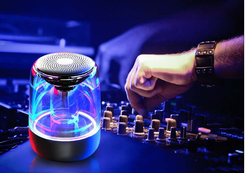 Portable Bluetooth speaker with colorful LED lights and DJ mixing in background.