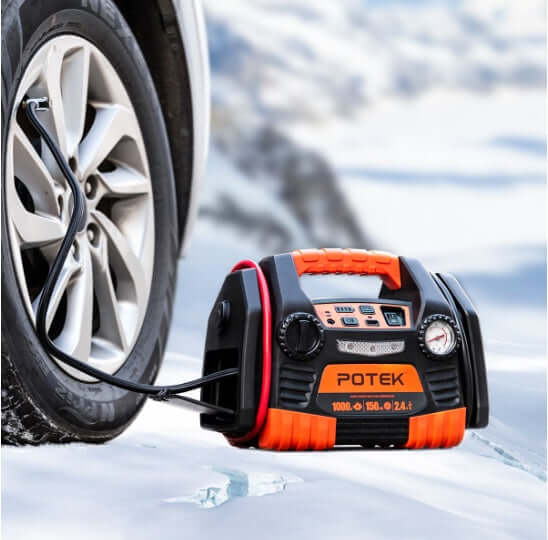 Portable battery jumper starter with air compressor inflating tire in snowy conditions. Compact design for emergency use.