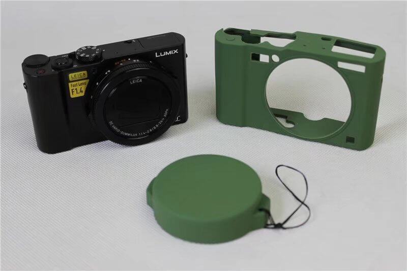 Silicone soft case camera bag in green with Lumix camera and lens cap on a white surface.