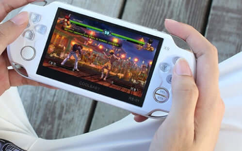 Person playing on a 4.3-inch handheld game console with vibrant graphics on the screen.
