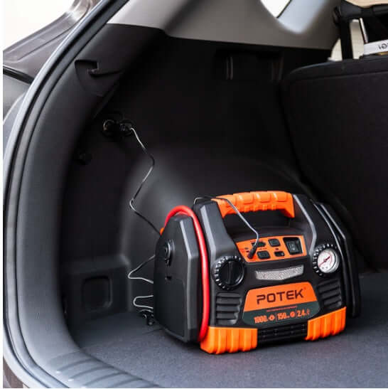 Portable battery jumper starter with air compressor in a car trunk, providing emergency jump-starting and USB charging.