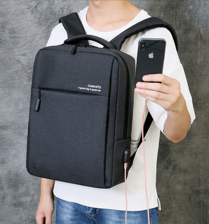 Man holding a smartphone while wearing a waterproof and shockproof laptop backpack, showcasing sleek Oxford cloth design.