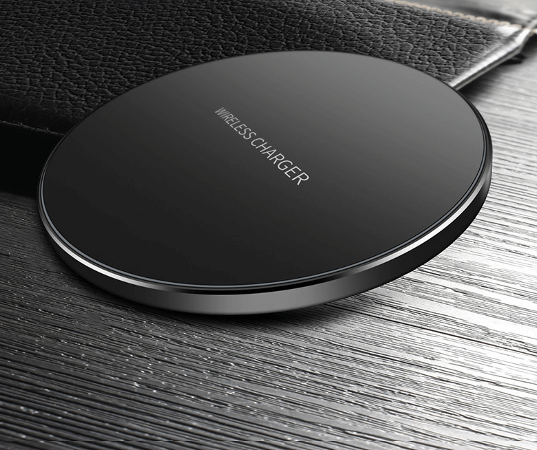 Wireless fast charge charger on wooden surface with leather wallet, sleek round design.