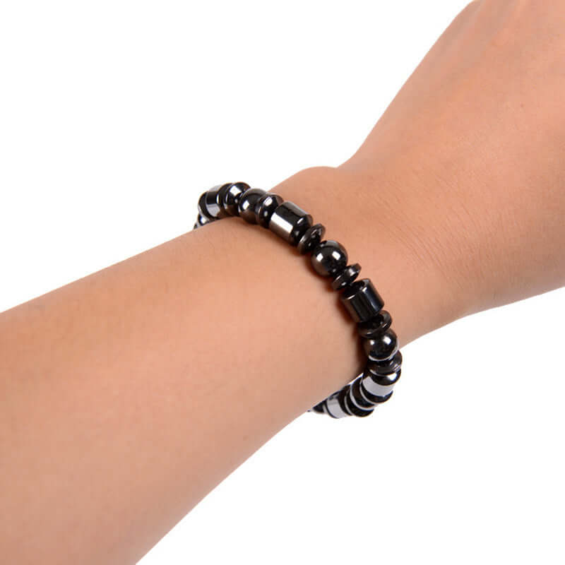 Black stone magnetic therapy bracelet on wrist, promoting weight loss and improved circulation.