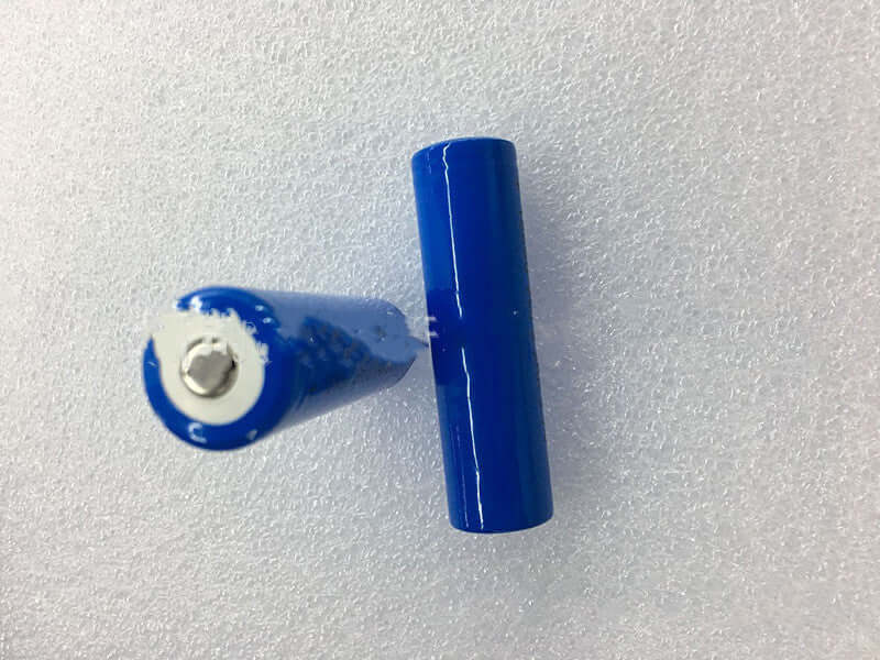 Two blue cylindrical batteries on a light background, showcasing their design and metal connectors.