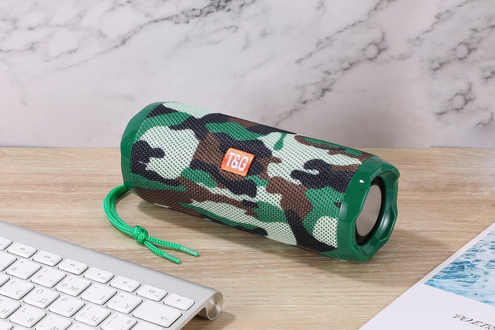 Camouflage fabric portable Bluetooth speaker with card holder on a desk next to a keyboard.