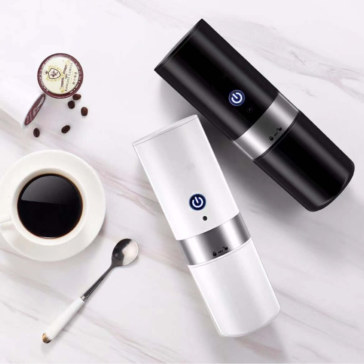 Portable fully automatic coffee machines in black and white, with coffee cup and spoon on marble surface.