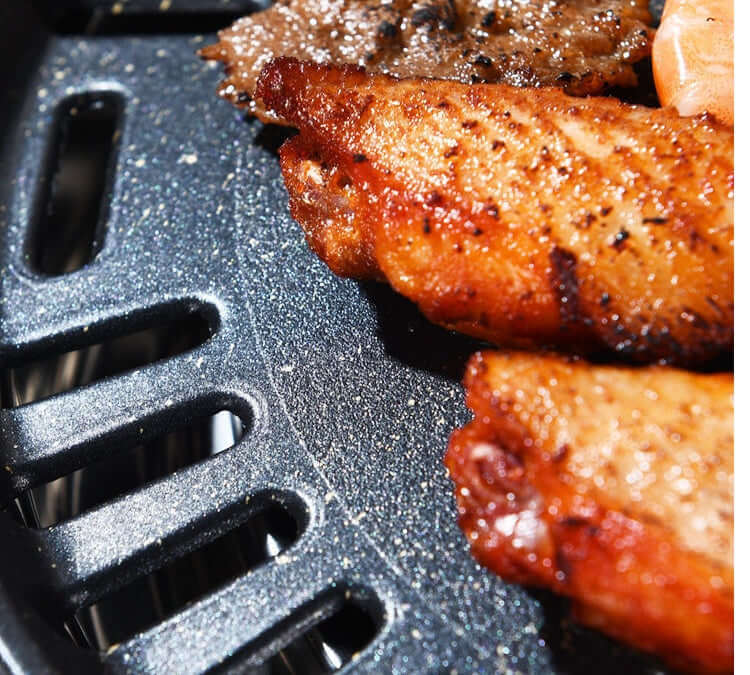 Close-up of grilled meat on a Korean stainless steel barbecue grill, showcasing charred skin and grilling texture.