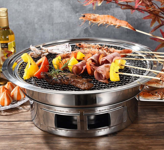 Korean stainless steel charcoal barbecue grill with assorted meats and vegetables, perfect for indoor or outdoor cooking.