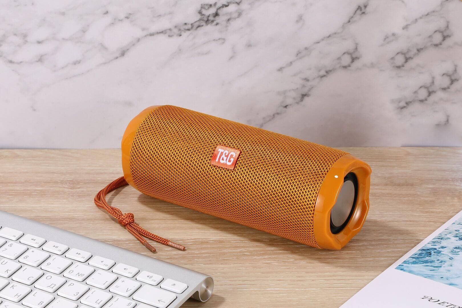 Fabric portable creative wireless Bluetooth speaker in orange color next to a keyboard.