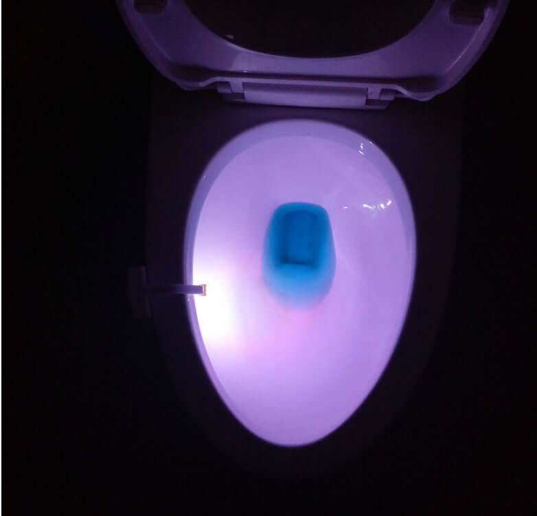 Illuminated toilet bowl with blue and purple LED light from a motion sensor night light.