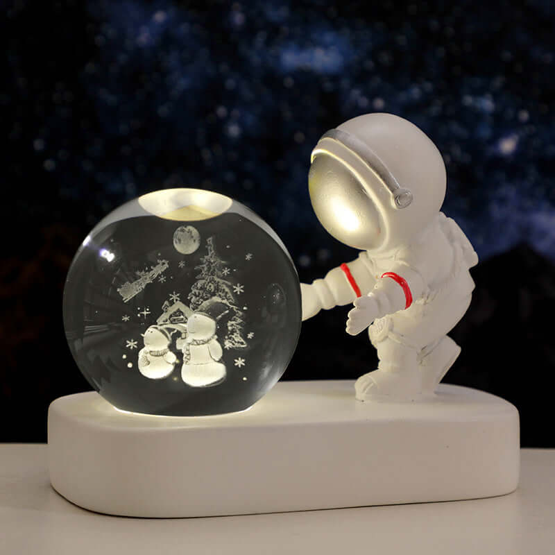 Astronaut figurine beside a glowing crystal ball night light depicting a winter scene, perfect for cozy atmospheres.