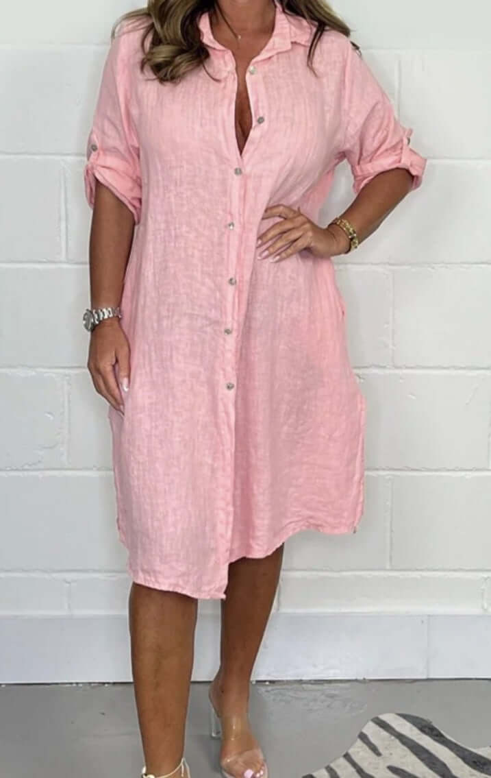 Woman wearing a loose casual half sleeve pink cotton linen shirt dress with button detail.