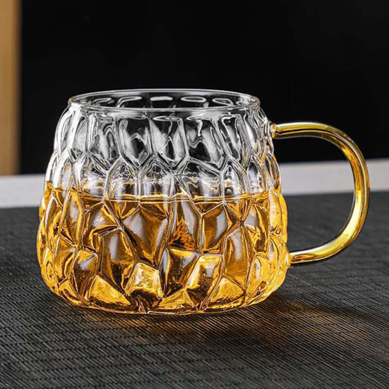 Stylish glass mug with a textured design, filled with a golden beverage, perfect for tea and drinks.