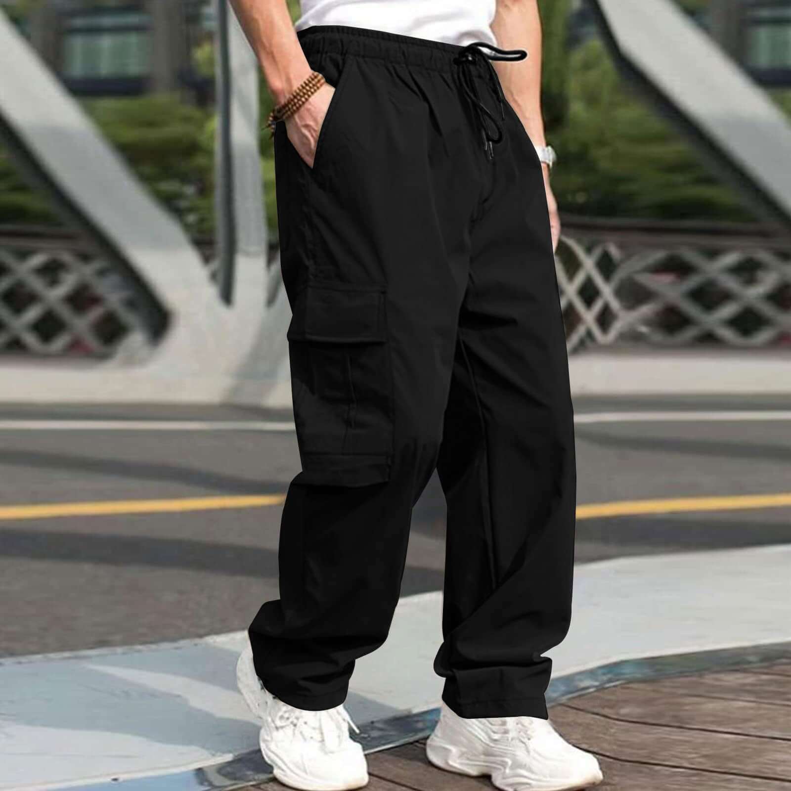 Casual black cargo pants for men with drawstring waist and pockets, styled for a relaxed fit in outdoor setting.