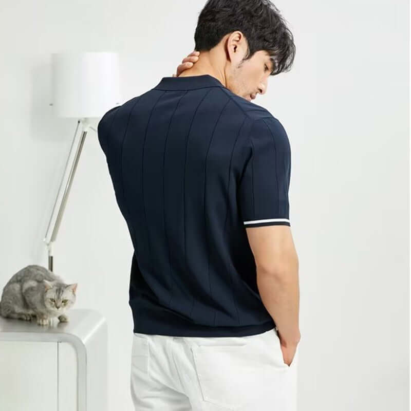 Stylish navy short-sleeved polo shirt with striped design, worn by a man, showcased in a modern indoor setting.