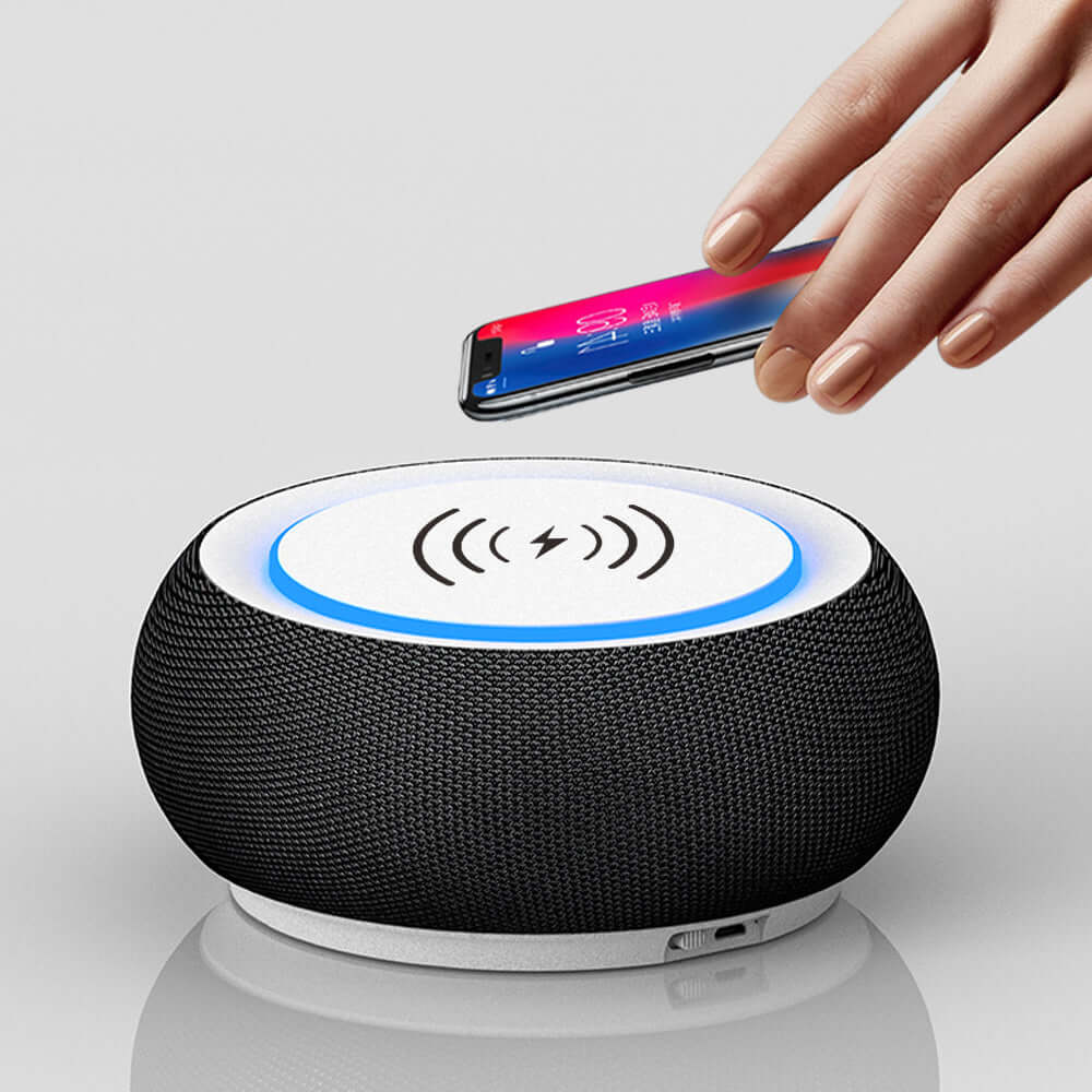 Wireless Bluetooth speaker with phone being placed on top for charging, featuring a sleek design and loud sound.