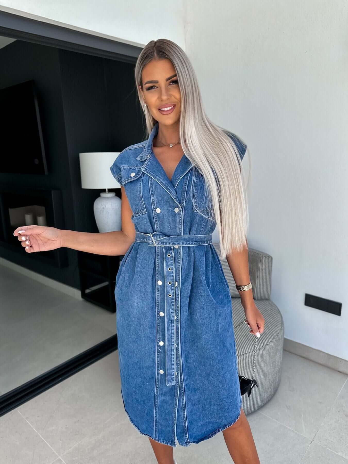Casual sleeveless denim dress with a polo collar, cinched waist, and A-line skirt in medium blue. Ideal for street style.