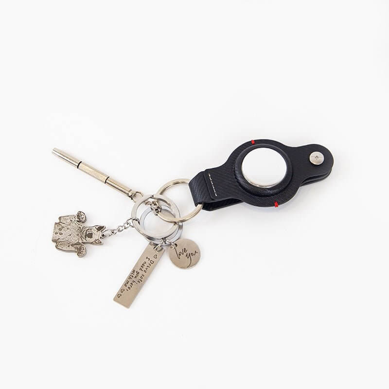Stylish AirTag holder with key ring, silver charms, and pen for Apple AirTag accessories.