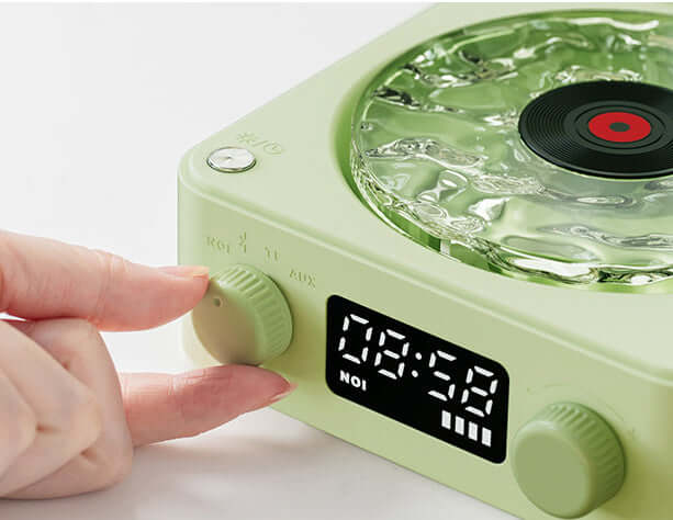 Close-up of a hand adjusting the knob of a retro turntable speaker with a vinyl design and digital clock display.