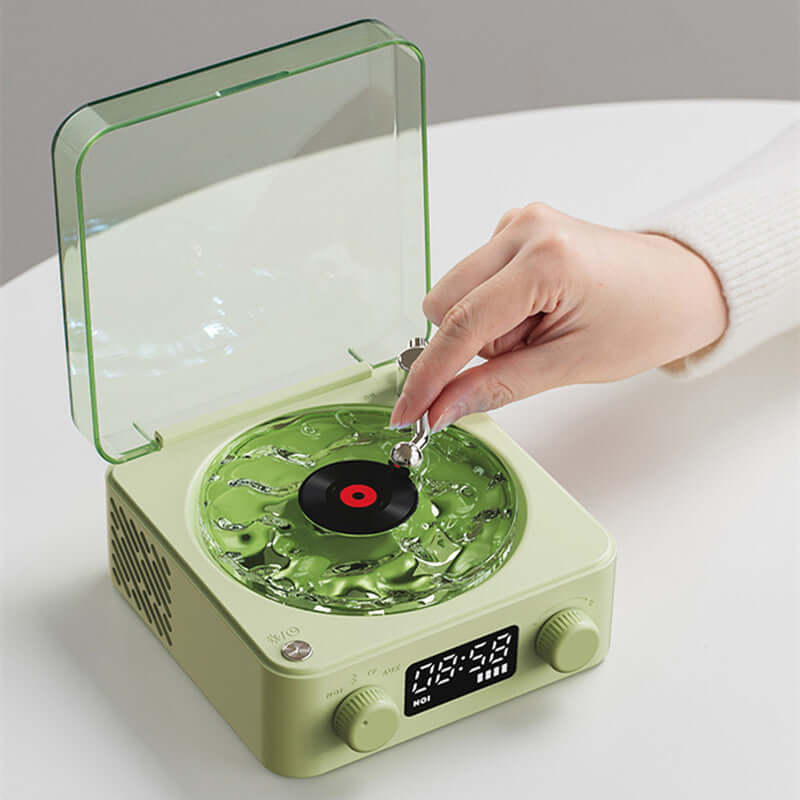 Person placing a vinyl record on a retro green turntable speaker with lid open.