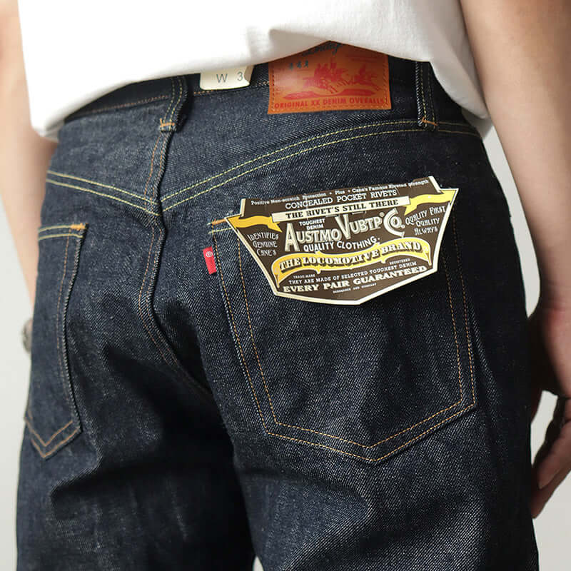 Close-up of the back pocket of dark indigo denim casual pants for men, showcasing the label and stitching details.