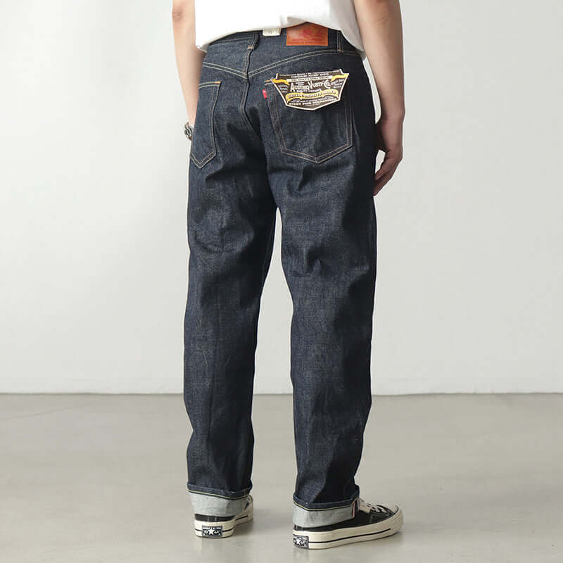 Back view of a man wearing dark indigo thickened denim pants with high waist and classic design.