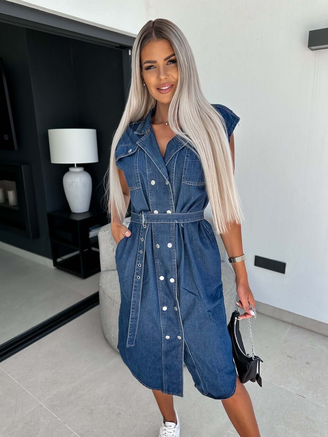Sleeveless denim dress with a polo collar, cinched waist, and pockets, styled in light blue denim.