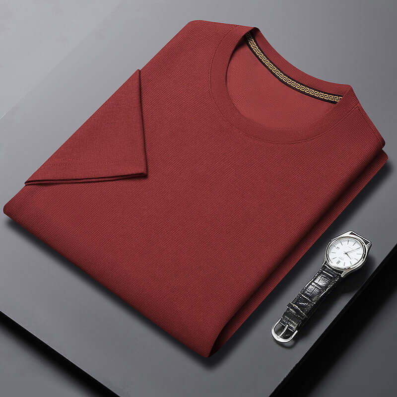 Men's breathable half sleeve round neck top in brick red, paired with a stylish watch on a dark surface.