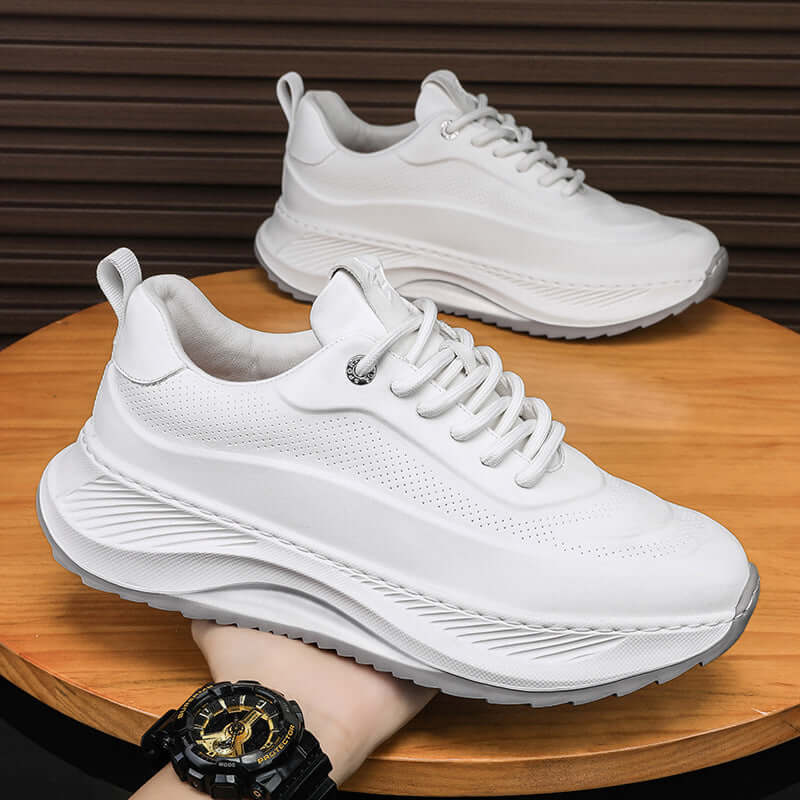 Stylish white thick-soled men's sports shoes with lace-up design on a wooden surface.